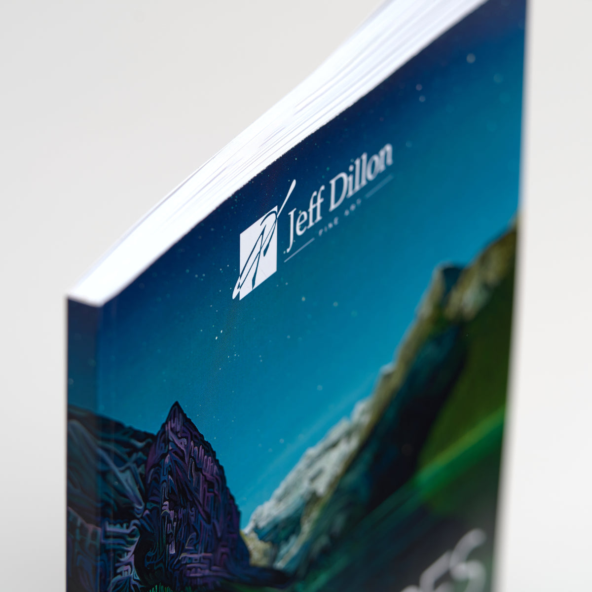 A close-up of the "Landscapes" Art Book by Jeff Dillon shows a Canadian mountain scene on the cover, with his logo and name at the top. The art book is slightly open, displaying its white pages inside.